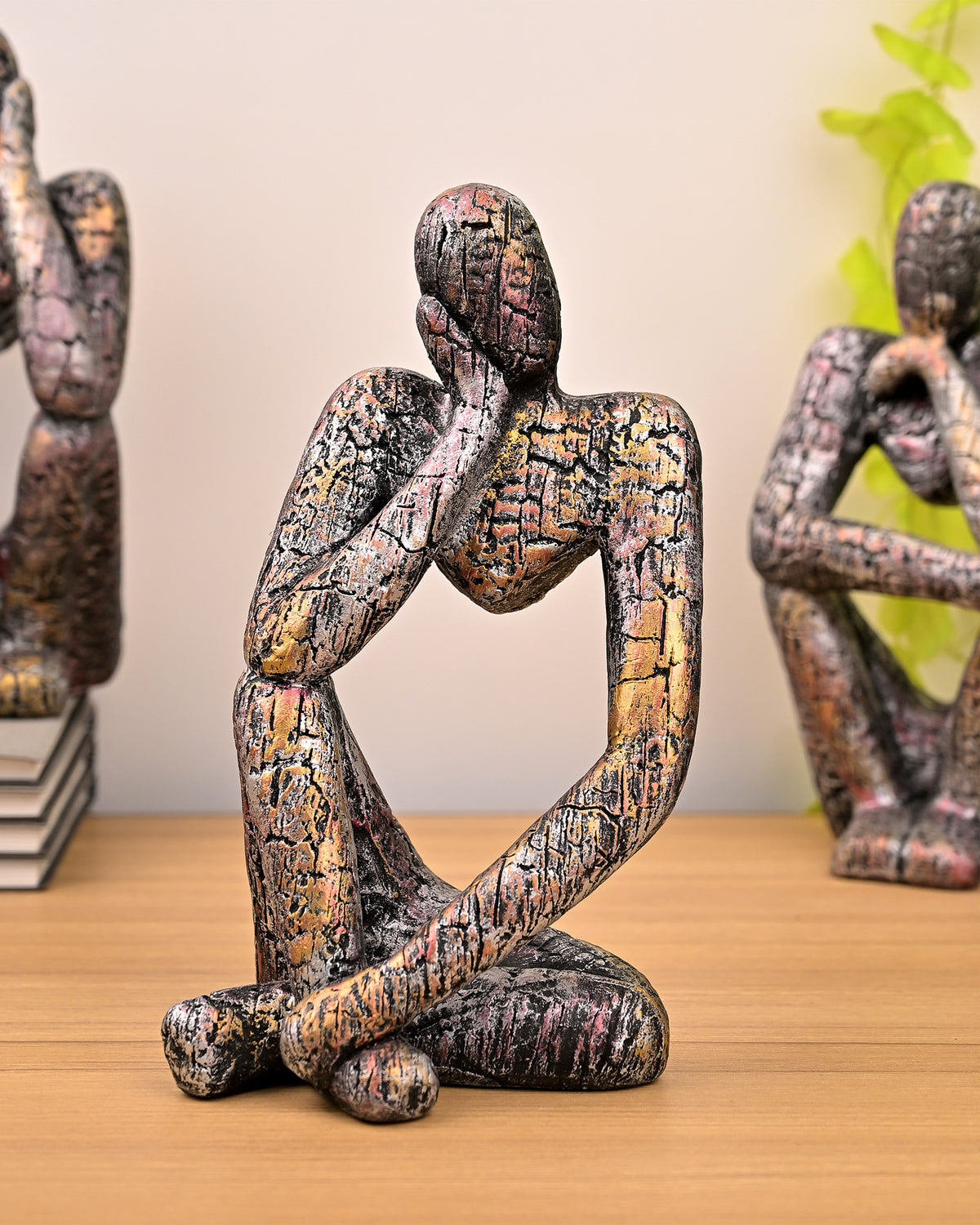 Three copper-finish thinking figurines arranged as a trio