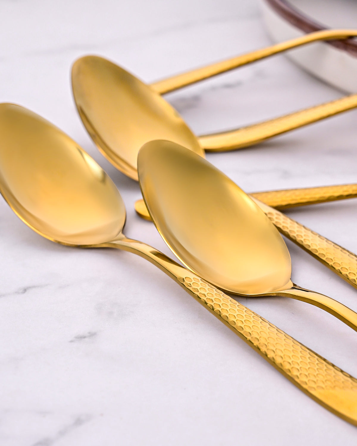 Close-Up View of Sunlit Gold Tea Spoons with Shiny Finish