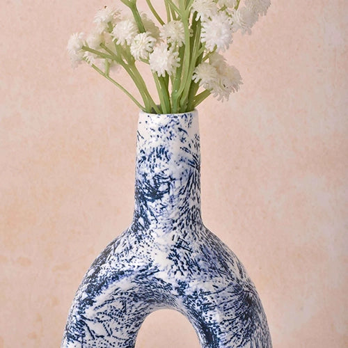 Sculptural blue ceramic vase with an open hollow shape

