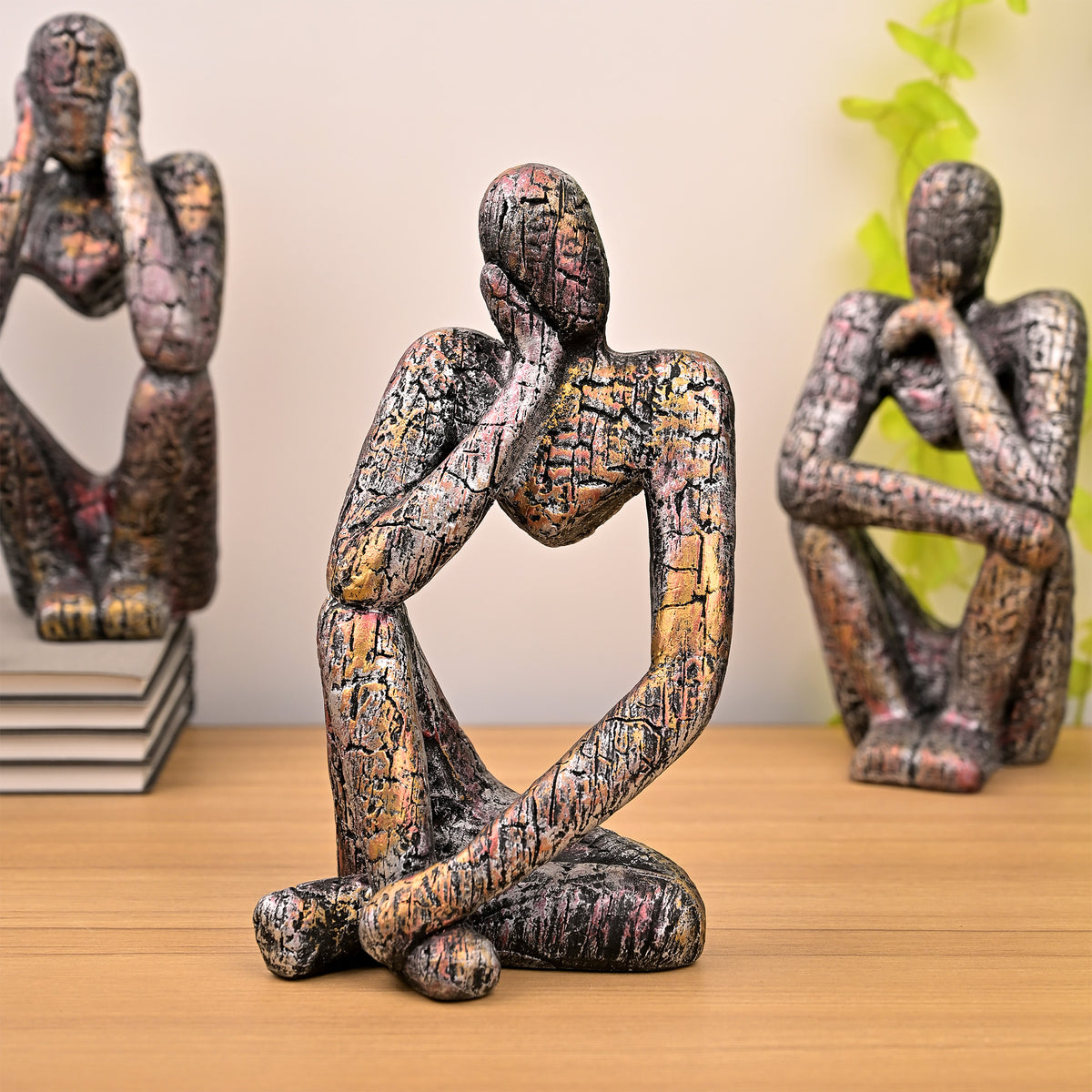 Three copper-finish thinking figurines arranged as a trio

